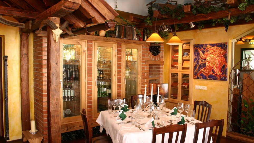 Bright restaurant featuring an elegant table, wine racks, and rustic wooden elements. | © Rudolf