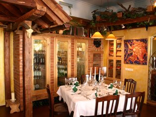 Bright restaurant featuring an elegant table, wine racks, and rustic wooden elements. | © Rudolf