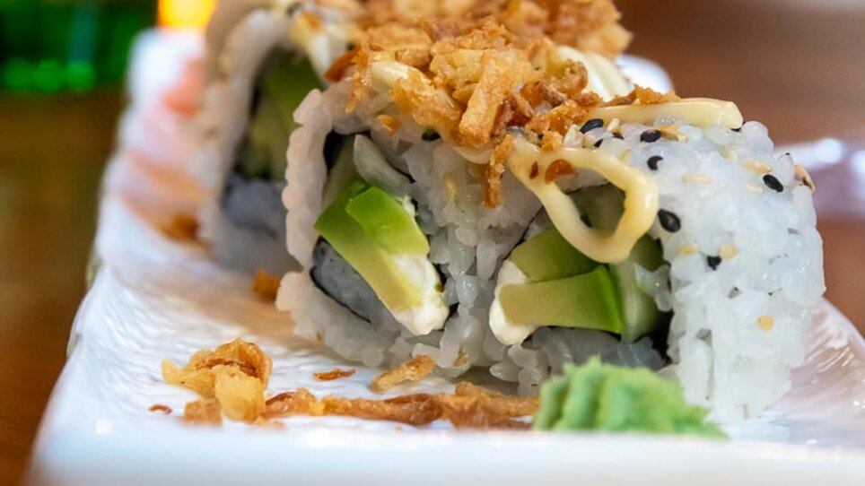 Delicious sushi with avocado, sesame, and onion chips.