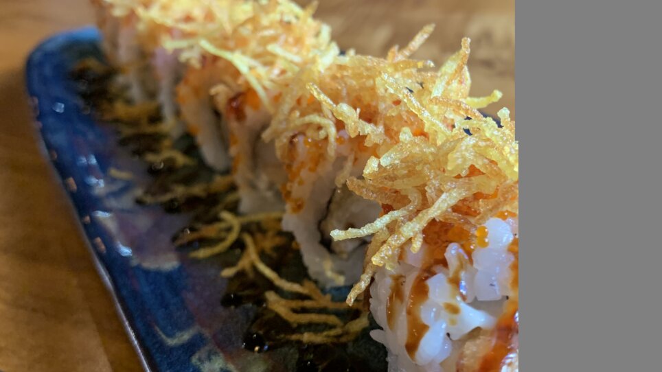 Delicious sushi with a crunchy topping on a plate in a restaurant.