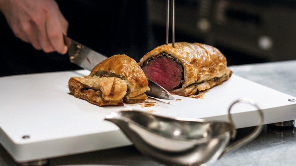 Ein Koch schneidet einen Beef Wellington in der Küche. | © Salon Marie