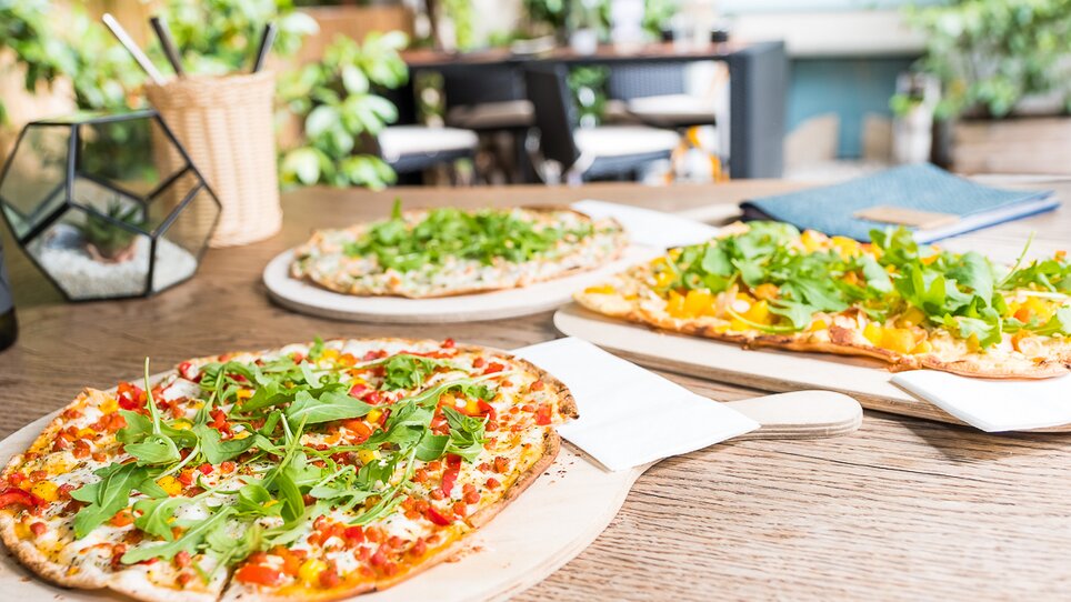 Drei verschiedene Pizzen mit frischen Zutaten auf einem Holztisch. | © Schäffner