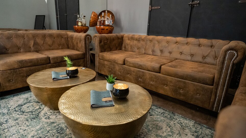 Gemütlicher Lounge-Bereich mit braunen Sofas und dekorativen Tischen. | © Schäffner