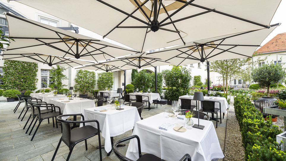 Cozy terrace with white tables and umbrellas in Graz. | © Paul Stajan