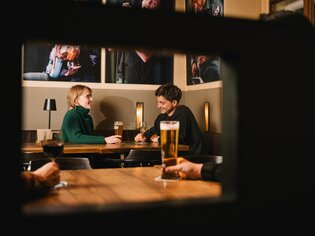 Paar an einem Tisch im Café Stockwerk mit Bier und Wein. | © G. Obetzhofer
