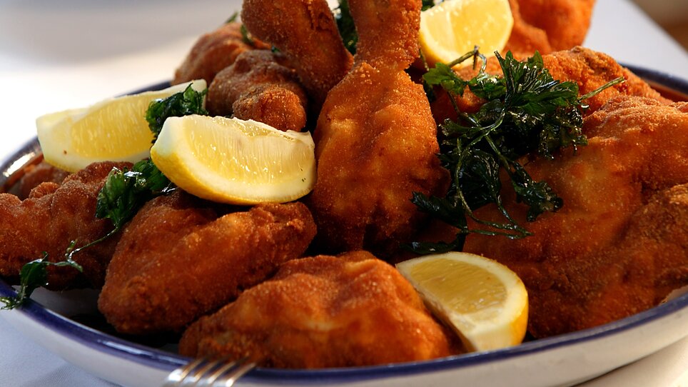 Steirisches Backhendl angerichtet mit Zitronenscheiben und Petersilie. | © Stoffbauer