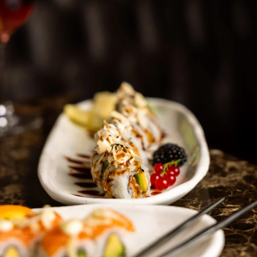 Close-up of sushi with fruit decoration and sauce. | © Subarashii