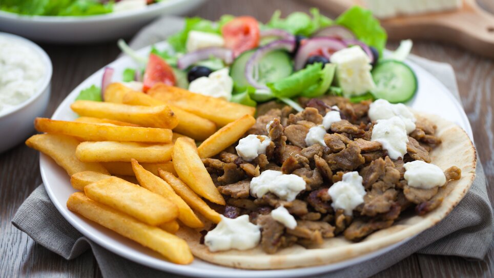 Plate with meat, fries, and salad at Restaurant Tinos.