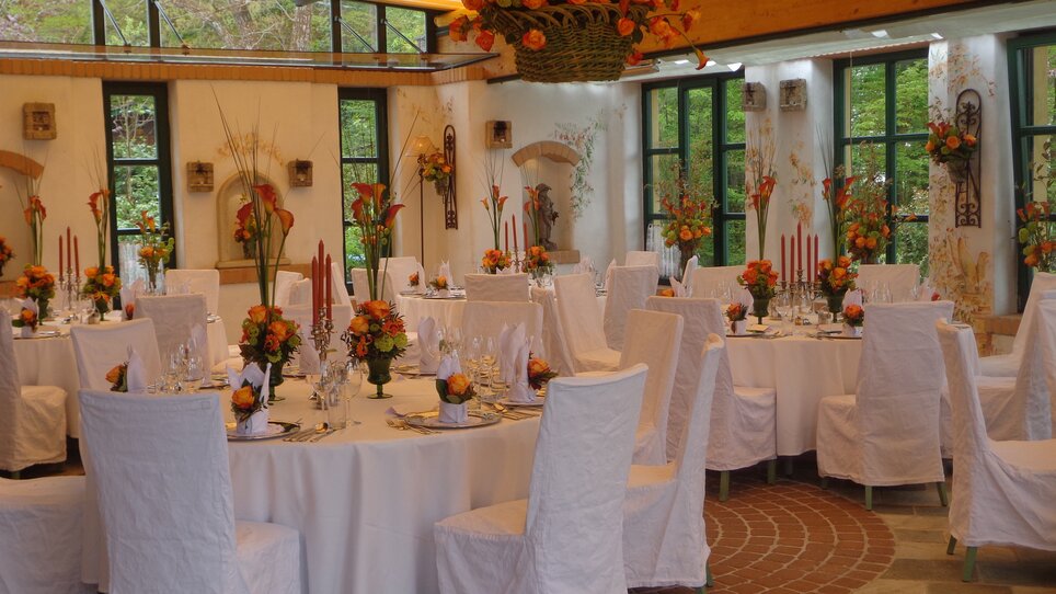 Elegant, flower-decorated event space with tables. | © Legenstein