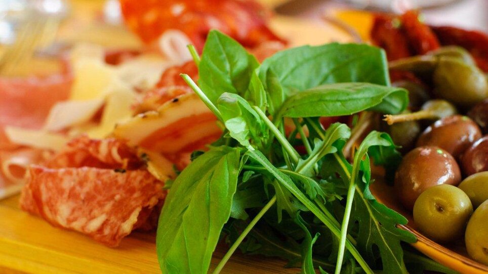 A presentation of fresh ingredients with meats, olives, and basil. | © Trattoria Siena