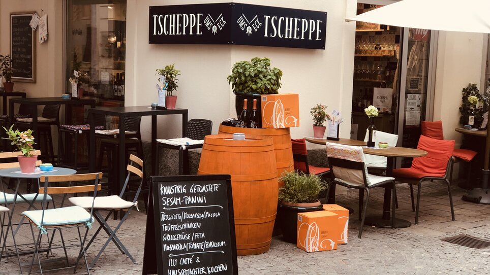 Cozy outdoor view of the Tscheppe Bar in Graz with outdoor seating and a menu for paninis. | © Tscheppe ums Eck