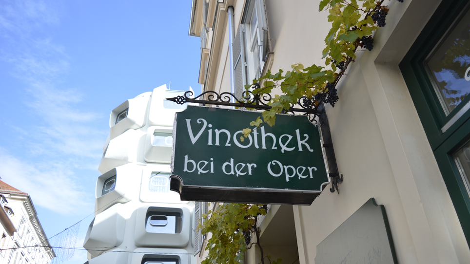 Un'insegna della Vinothek bei der Oper a Graz, circondata da viti. | © Vinothek bei der Oper