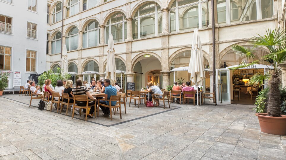 Gemütliche Weinbar im Innenhof mit Gästen in Graz. | © Klapotetz