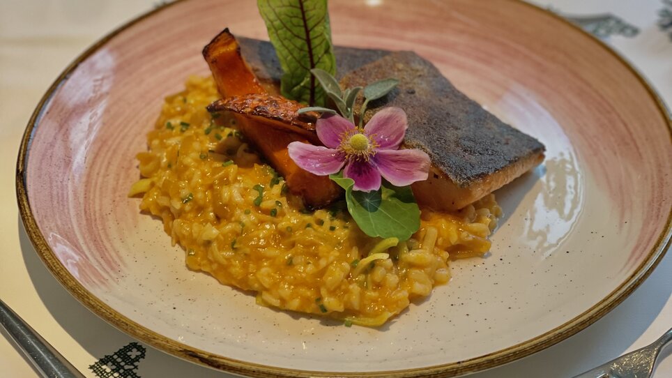 Ein schön angerichteter Teller mit gebratenem Fisch auf Risotto. | © Gasthaus Zur Schmiedn