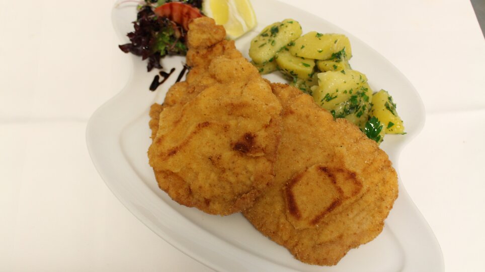 Two large schnitzels on a plate with potatoes and salad. | © Zur alten Press