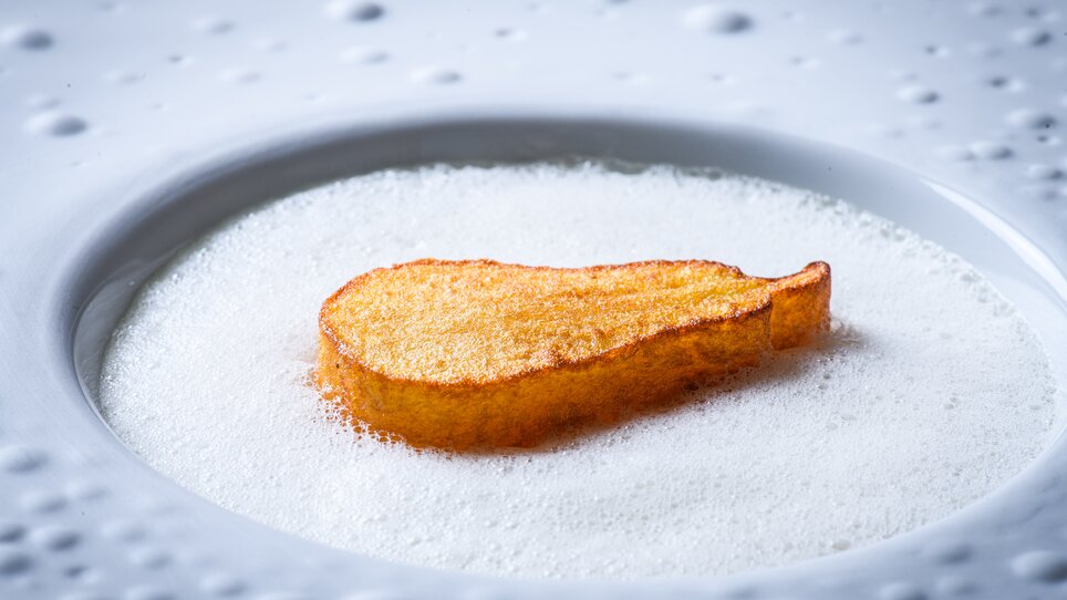 Ein kunstvoll angerichtetes Gericht mit einem knusprigen Stück und Schaum. | © Jürgen Schmücking