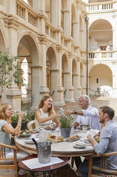 Eine Gruppe von vier Personen genießt ein geselliges Essen im Innenhof des Landhauses. | © Graz Tourismus - Astrid Schwab