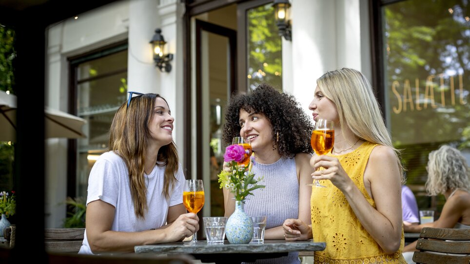 Tre donne che gustano drink a un tavolo all'aperto. | © Graz Tourismus - Tom Lamm