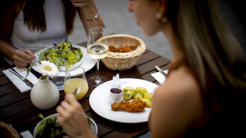 Zwei Frauen genießen ein köstliches Essen mit Salat, Backhendl und Getränken. | © Graz Tourismus - Tom Lamm
