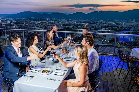 Sonnenuntergang über Graz mit Freunden beim Essen und Trinken auf einer Dachterrasse. | © Graz Tourismus - Mias Photoart