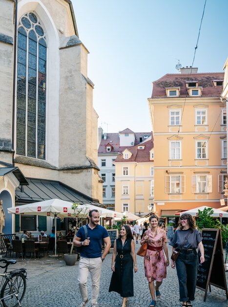 Graz - la Capitale dei Sapori | © Graz Tourismus - Mias Photoart-4 Quattro persone passeggiano a Graz in una giornata di sole. | © Graz Tourismus - Mias Photoart-4