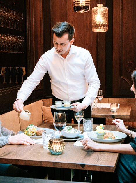 Zum Abendessen in Graz: Kellner serviert delikate Speisen an einem Tisch. | © Graz Tourismus