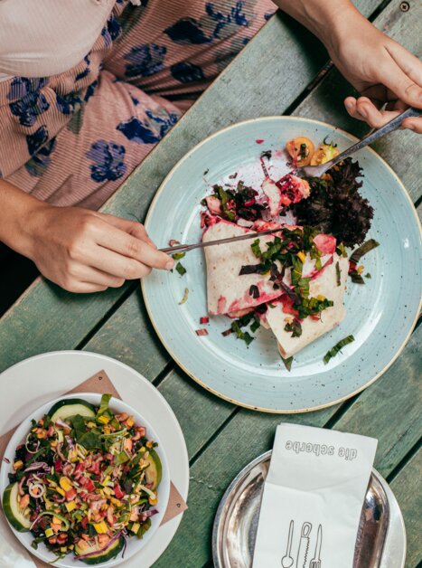 Eine Person isst ein leckeres Gericht in Graz, während eine Gitarre neben ihr liegt. | © Graz Tourismus