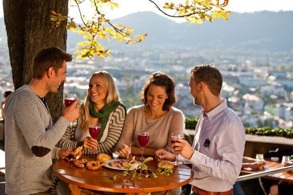 Freunde genießen Getränke und Snacks in Graz mit Blick auf die Stadt. | © Graz Tourismus - Tom Lamm