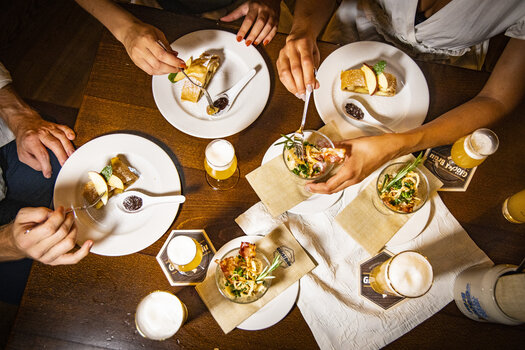 Various dishes and beers on a table during a meal. | © Graz Tourismus - Werner Krug