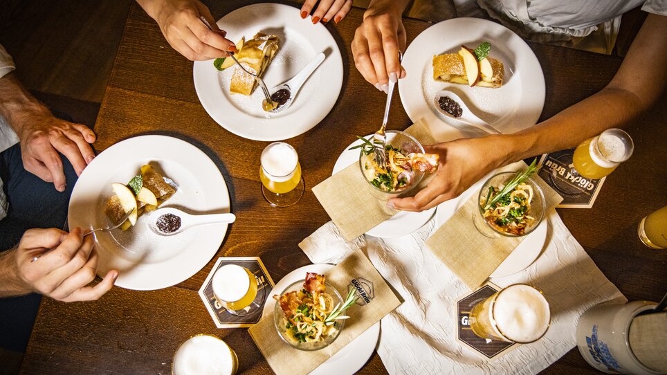 Verschiedene Gerichte und Biere auf einem Tisch beim Essen. | © Graz Tourismus - Werner Krug