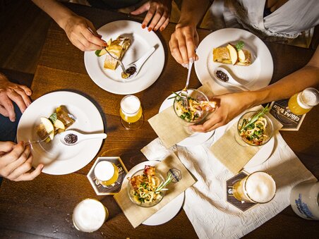 Culinary beer tour in Graz | © Graz Tourismus - Werner Krug Various dishes and beers on a table during a meal. | © Graz Tourismus - Werner Krug