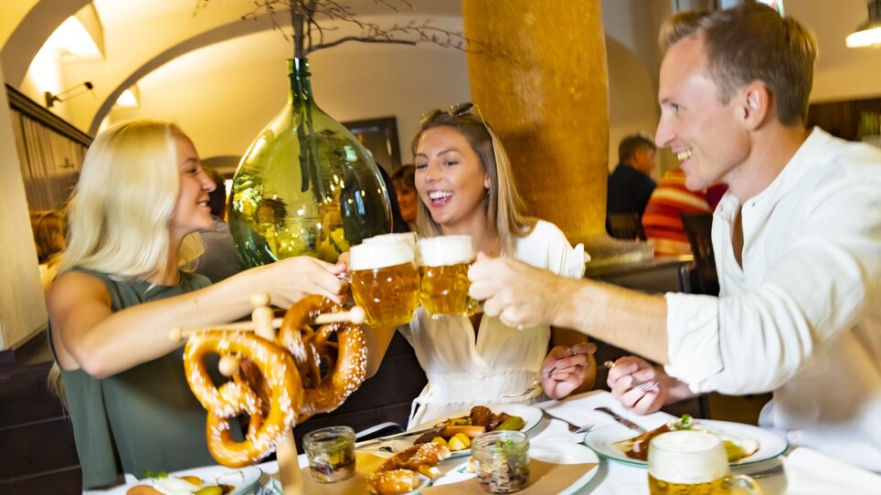 Freunde stoßen mit Bier an und genießen Essen in Graz. | © Graz Tourismus - Werner Krug