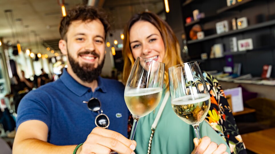 Ein Paar hebt Gläser mit Wein an, um zu feiern. | © Graz Tourismus - Werner Krug