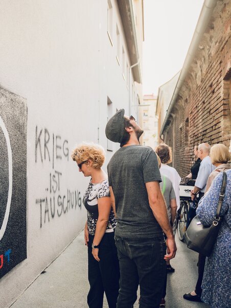 A group of people in an alley with graffiti in Graz. | © Graz Tourismus - Lupi Spuma