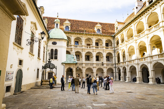 Eine Gruppe von Touristen im Innenhof eines historischen Gebäudes in Graz, umgeben von Säulen und Bögen. | © Graz Tourismus - Werner Krug