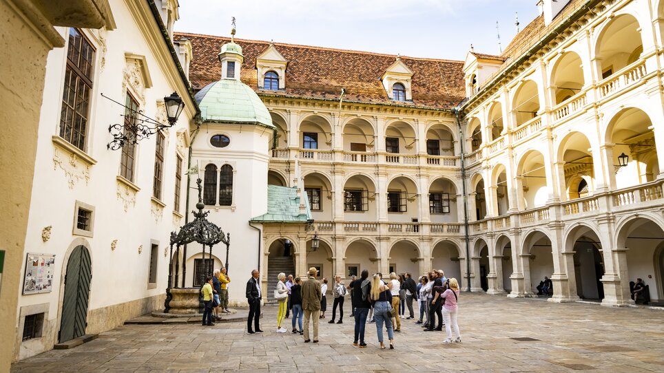 Eine Gruppe von Touristen im Innenhof eines historischen Gebäudes in Graz, umgeben von Säulen und Bögen. | © Graz Tourismus - Werner Krug
