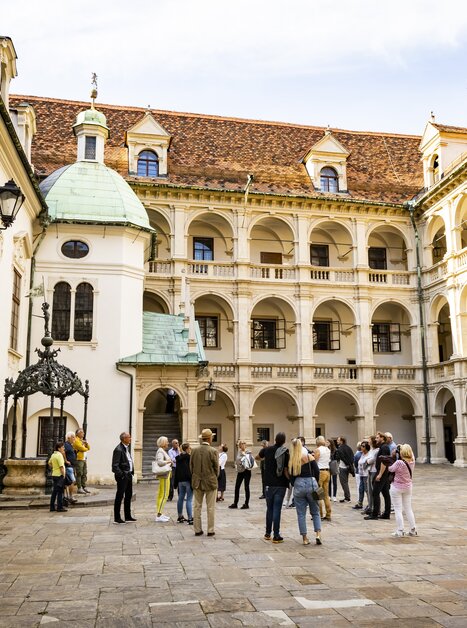 Eine Gruppe von Touristen im Innenhof eines historischen Gebäudes in Graz, umgeben von Säulen und Bögen. | © Graz Tourismus - Werner Krug