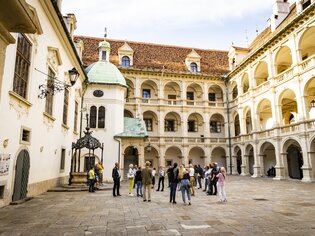 Eine Gruppe von Touristen im Innenhof eines historischen Gebäudes in Graz, umgeben von Säulen und Bögen. | © Graz Tourismus - Werner Krug