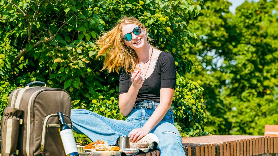 Junge Frau genießt ein Picknick im Freien, umgeben von Natur. | © Mias Photoart