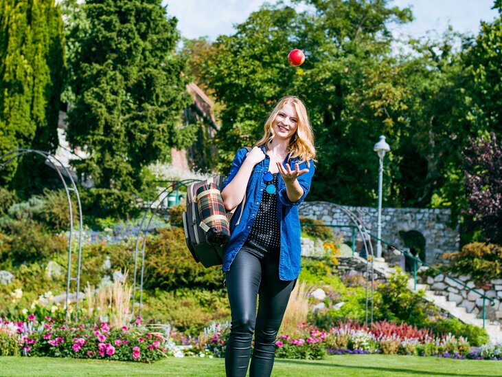 A woman enjoys a picnic in the park with the Graz clock tower in the background. | © Mias Photoart