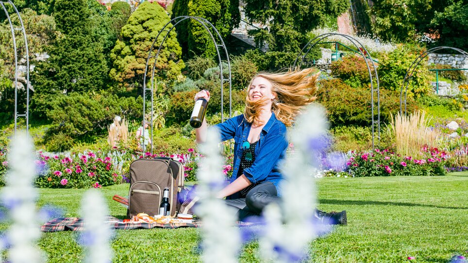 Junge Frau genießt ein Picknick in Graz mit Blick auf bunte Blumen. | © Mias Photoart
