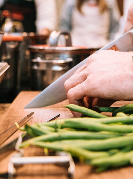 A chef is slicing green beans while others are working in the kitchen. | © Graz Tourismus