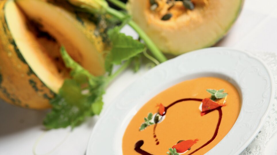 Fine pumpkin soup in an elegant plate, surrounded by pumpkin. | © Graz Tourismus - Harry Schiffer