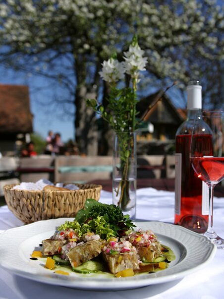 Un piatto di pesce e verdure, vino rosato sullo sfondo. | © Graz Tourismus - Harry Schiffer