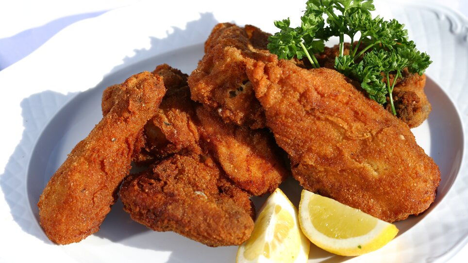 Leckere, knusprige frittierte Hühnchenstücke mit Zitronen und Petersilie. | © Graz Tourismus - Harry Schiffer
