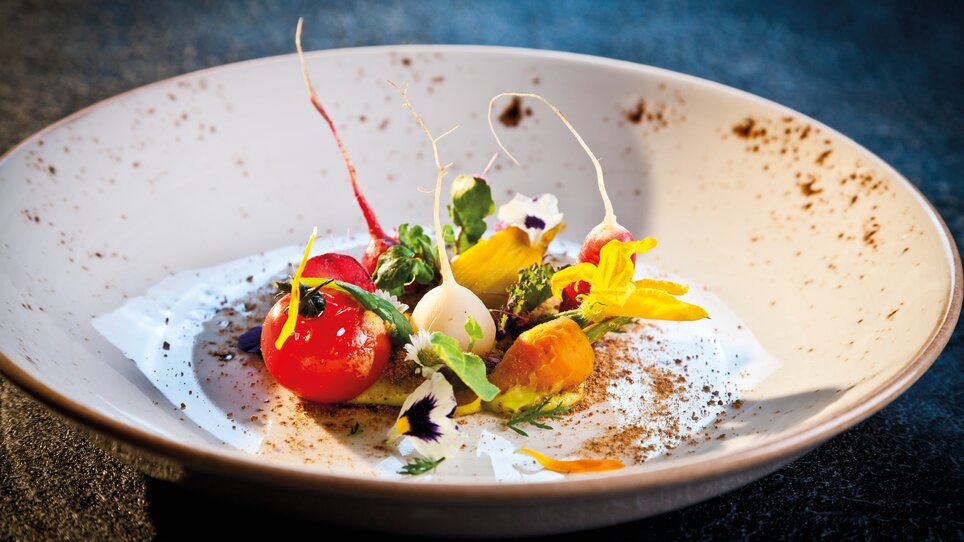 An artistically arranged gourmet dish featuring colorful ingredients and flowers. | © Graz Tourismus - Werner Krug
