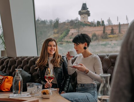 Zwei Frauen im Tagescafé Freiblick in Graz mit Graz Uhrturm im Hintergrund. | © 5komma5sinne - Rene Strasser Fotografie 