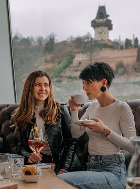 Zwei Frauen im Tagescafé Freiblick in Graz mit Graz Uhrturm im Hintergrund. | © 5komma5sinne - Rene Strasser Fotografie 