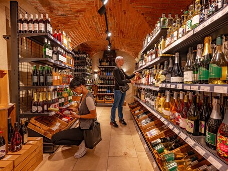 Kaufende Personen in einem Weingeschäft mit Regalen voller Flaschen. | © 5komma5sinne - Rene Strasser Fotografie