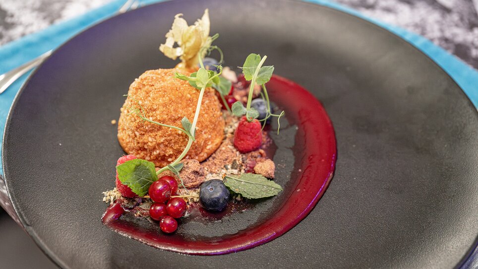 Ein feines Dessert mit Beeren und Sauce, präsentiert auf einem eleganten Teller. | © 5komma5sinne - Rene Strasser Fotografie